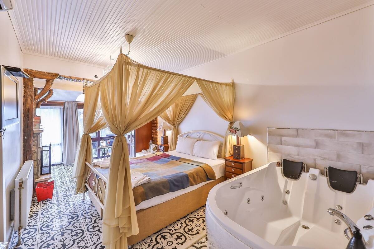 Une chambre spacieuse avec un grand lit, un coin salon séparé et une baignoire.