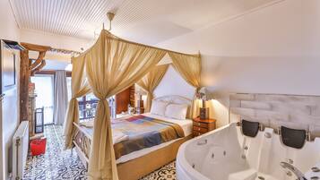 Een ruime slaapkamer met een groot bed, een afzonderlijke zithoek en een badkuip.