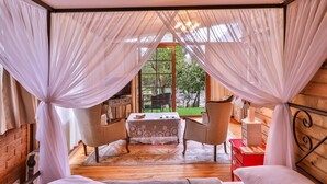 Ein Schlafzimmer mit großem Fenster, einem Bett, einem Tisch und zwei Stühlen.