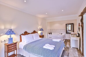 Une chambre à coucher comprenant un lit, des lampes de chevet, une table de chevet, une commode, une coiffeuse et une baignoire.