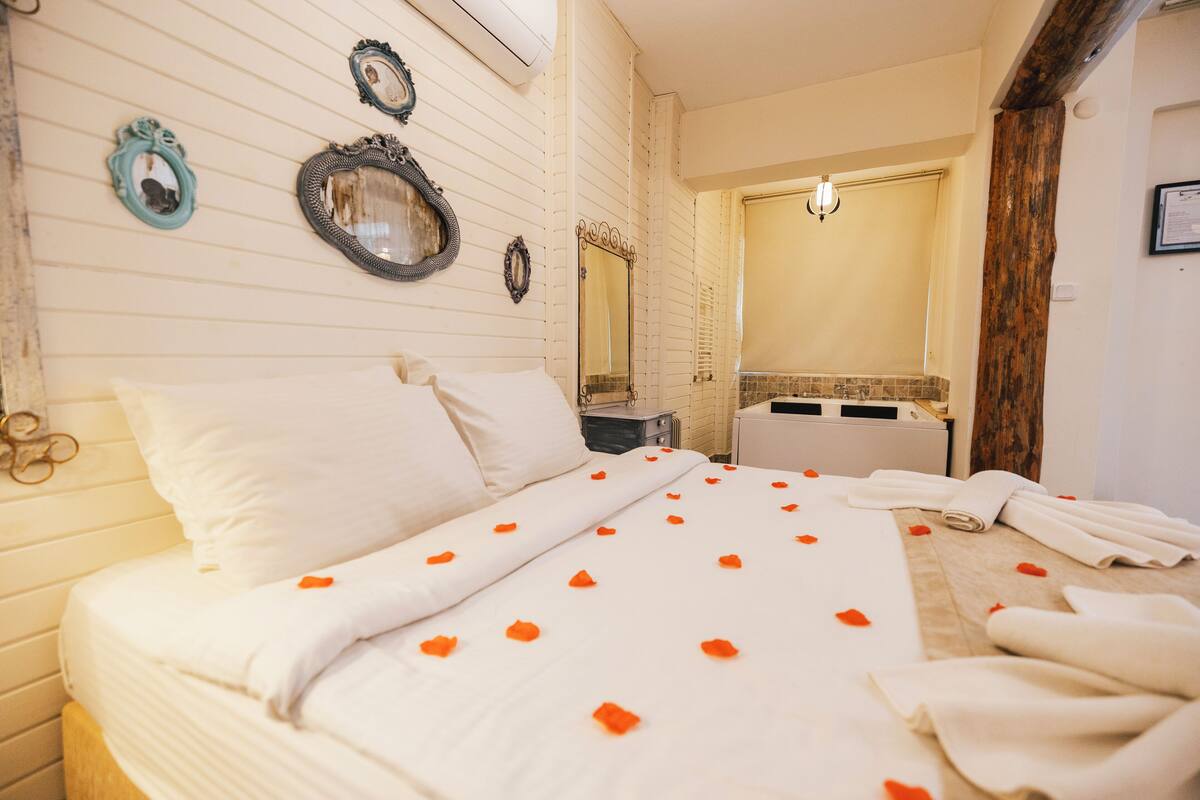Une chambre d’hôtel avec un lit, un miroir et une salle de bain visible à travers une porte ouverte.