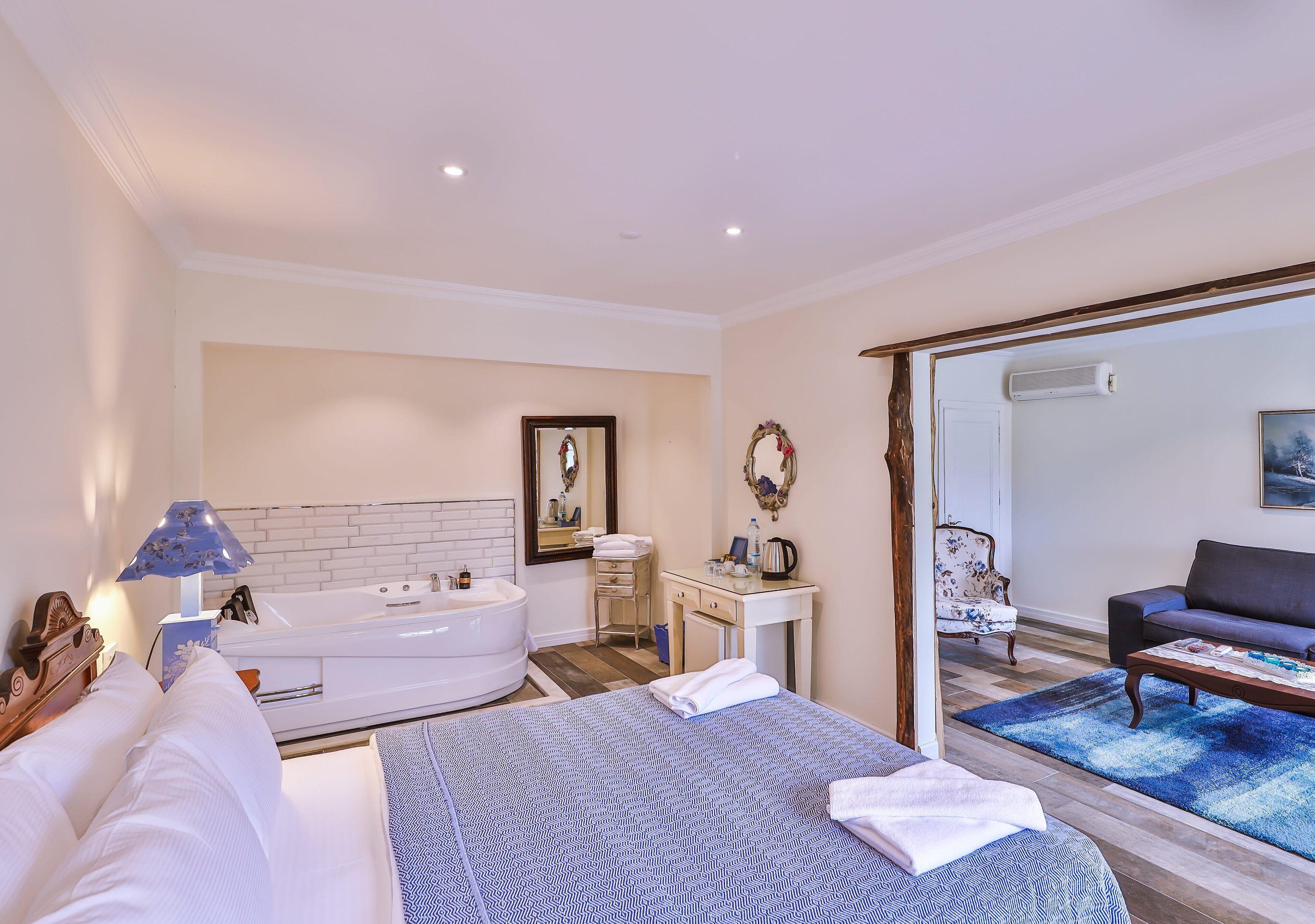 Un dormitorio con una cama grande, un baño con bañera, un escritorio y un sofá en la sala de estar.