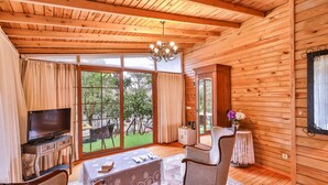 Ein Interieur einer Holzhütte mit Fernseher, Esstisch und einem Stuhl.