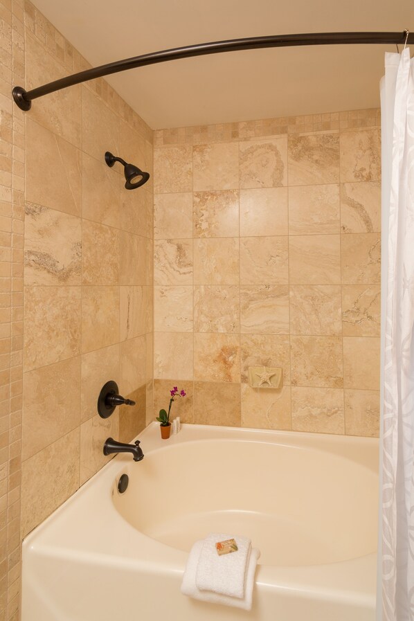 A bathroom with a bathtub, a showerhead, and a towel rack.