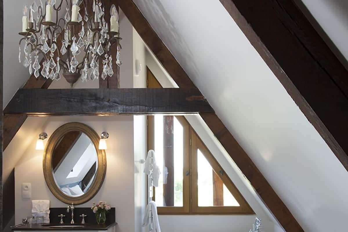Une chambre à coucher avec un grand lit, une coiffeuse avec un miroir, un lustre et une baignoire.
