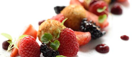 A dessert plate with raspberries, blackberries, and a scoop of ice cream.