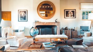 Un salon chaleureux avec une cheminée, des fauteuils confortables, un globe terrestre et des livres.