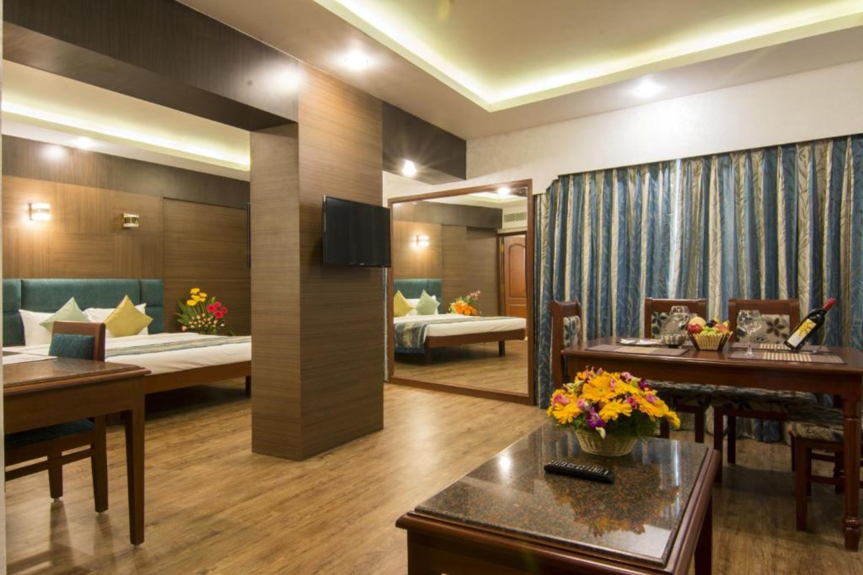 A hotel room with a bed, a desk, a chair, a table, and a TV.