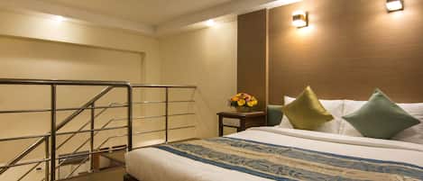 A hotel room with a bed, a nightstand, a flower vase, and a staircase.