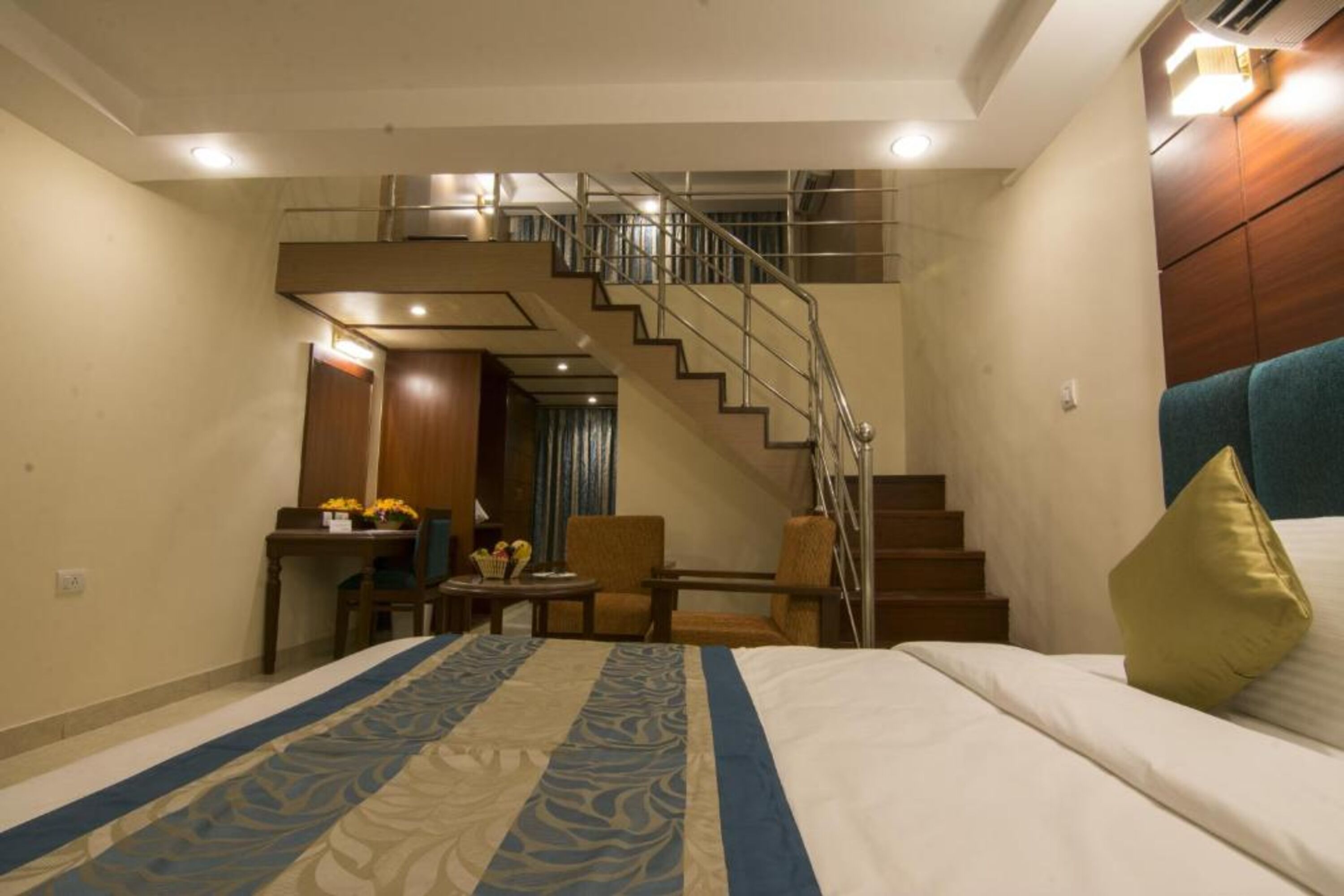 Une chambre d’hôtel avec un lit, un bureau, une chaise, un escalier et une vue sur l’extérieur.