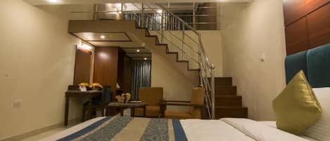 Une chambre d’hôtel avec un lit, un bureau, une chaise, un escalier et une vue sur l’extérieur.