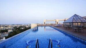 A rooftop infinity pool with a clear view of the cityscape, a glass gazebo, and lounge chairs. - Shenbaga Hotel and Convention Centre (Puducherry)