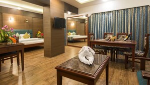 A hotel room with a bed, a sitting area with a table and chairs, a small rug, and a decorative towel on the table. - Shenbaga Hotel and Convention Centre (Puducherry)