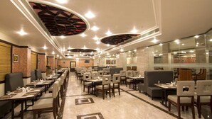 A spacious restaurant with multiple dining tables and chairs, a modern ceiling design, and a clean, well-lit interior. - Shenbaga Hotel and Convention Centre (Puducherry)