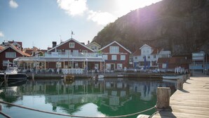 Un hotel frente al agua con muelle, barcos y montañas al fondo.