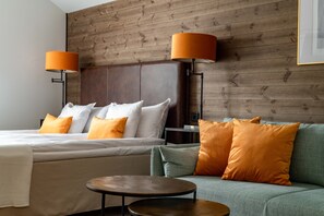 A hotel room with a large bed, two bedside lamps, a green sofa, and a small round table. - Bryggan Fjällbacka (Fjallbacka)