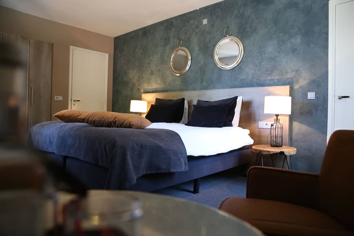 Une chambre d’hôtel moderne avec un grand lit, deux lampes de chevet, une petite table ronde et une chaise.