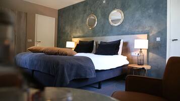 Una habitación de hotel moderna con una cama grande, dos lámparas de noche, una mesita redonda y una silla.