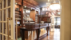Een bar met houten meubels, een kroonluchter en een spiegel die het interieur weergeeft.