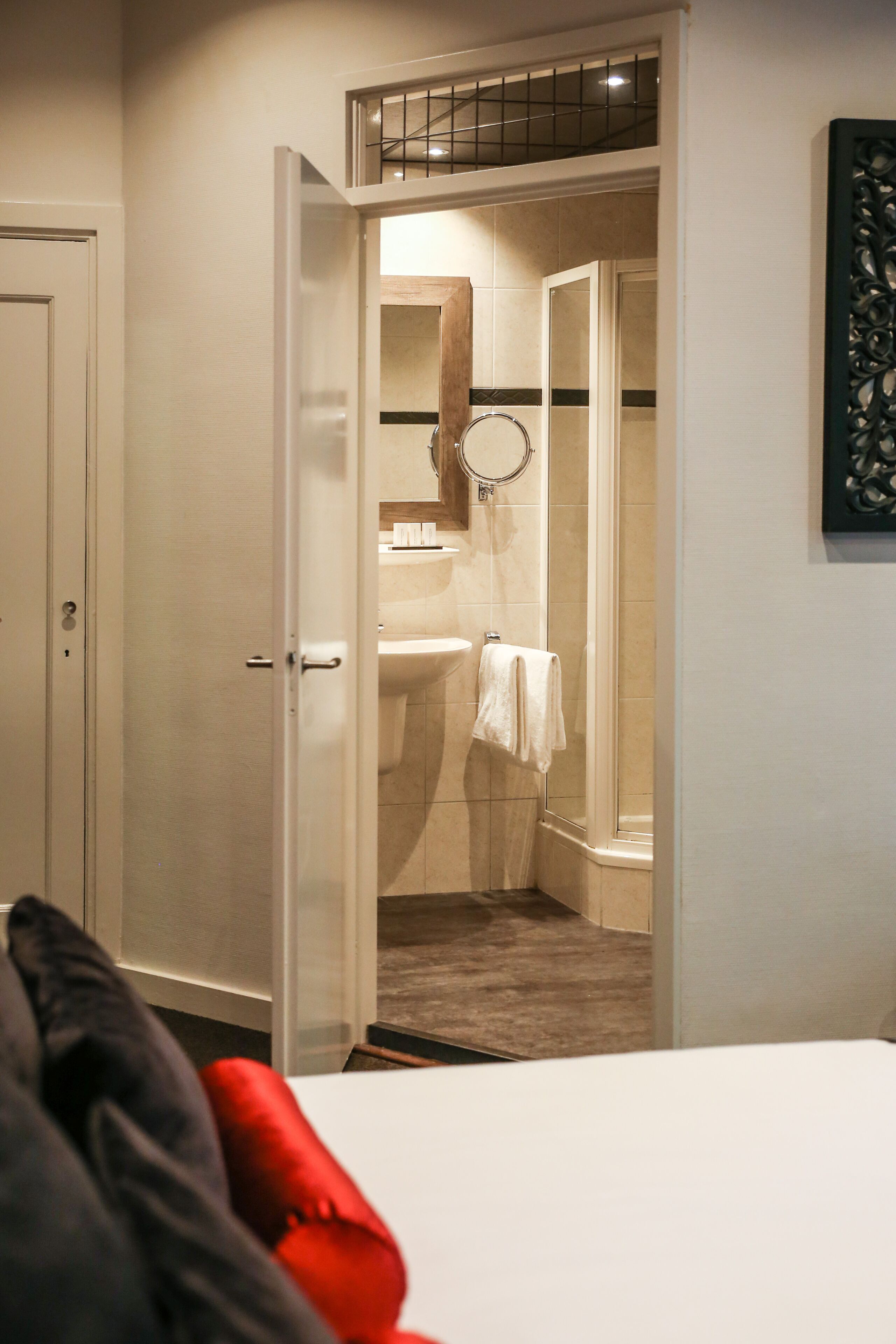 Een hotelkamer met een bed, een kast en een badkamer met douche en wastafel.