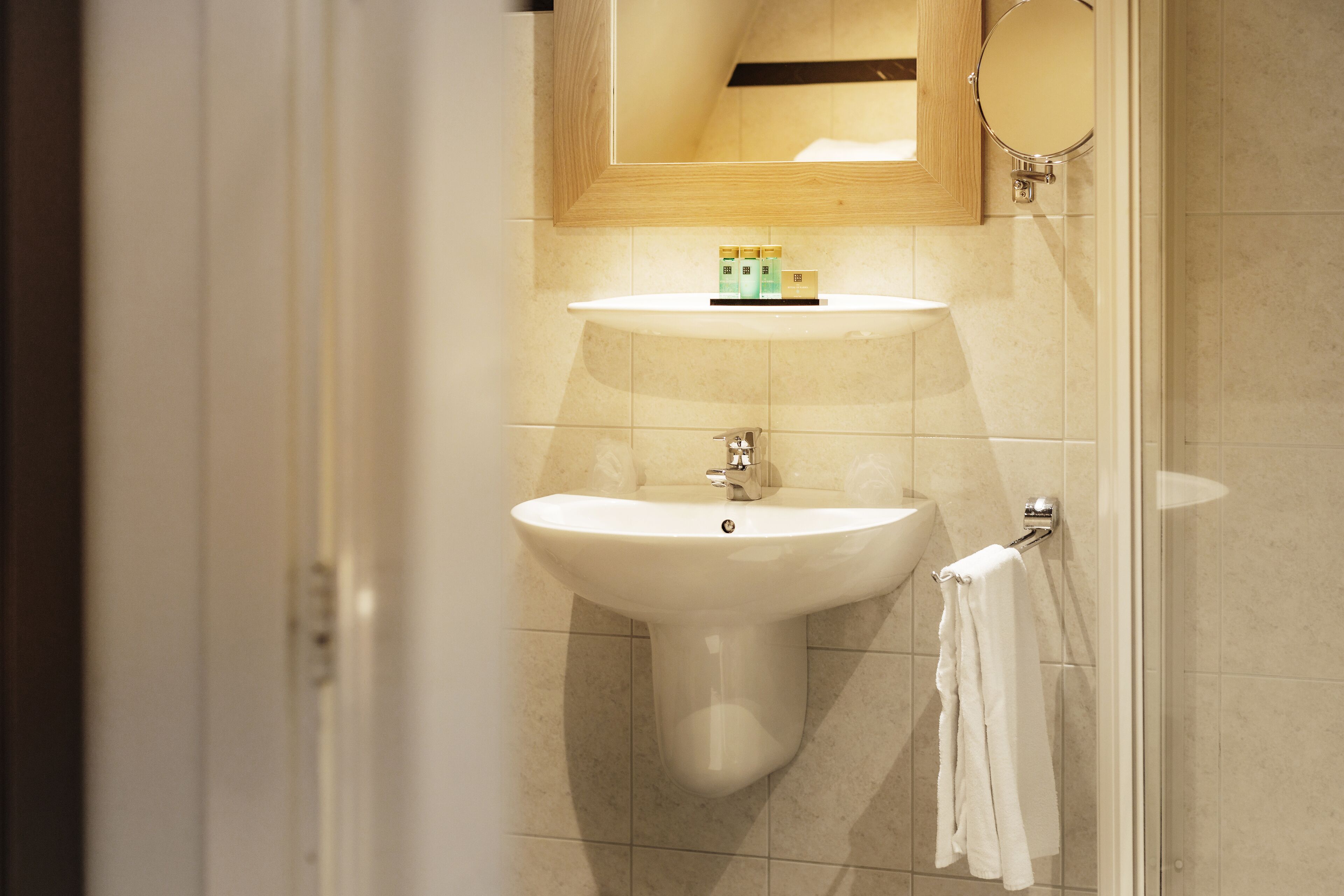 A bathroom with a sink, mirror, and towel rack.