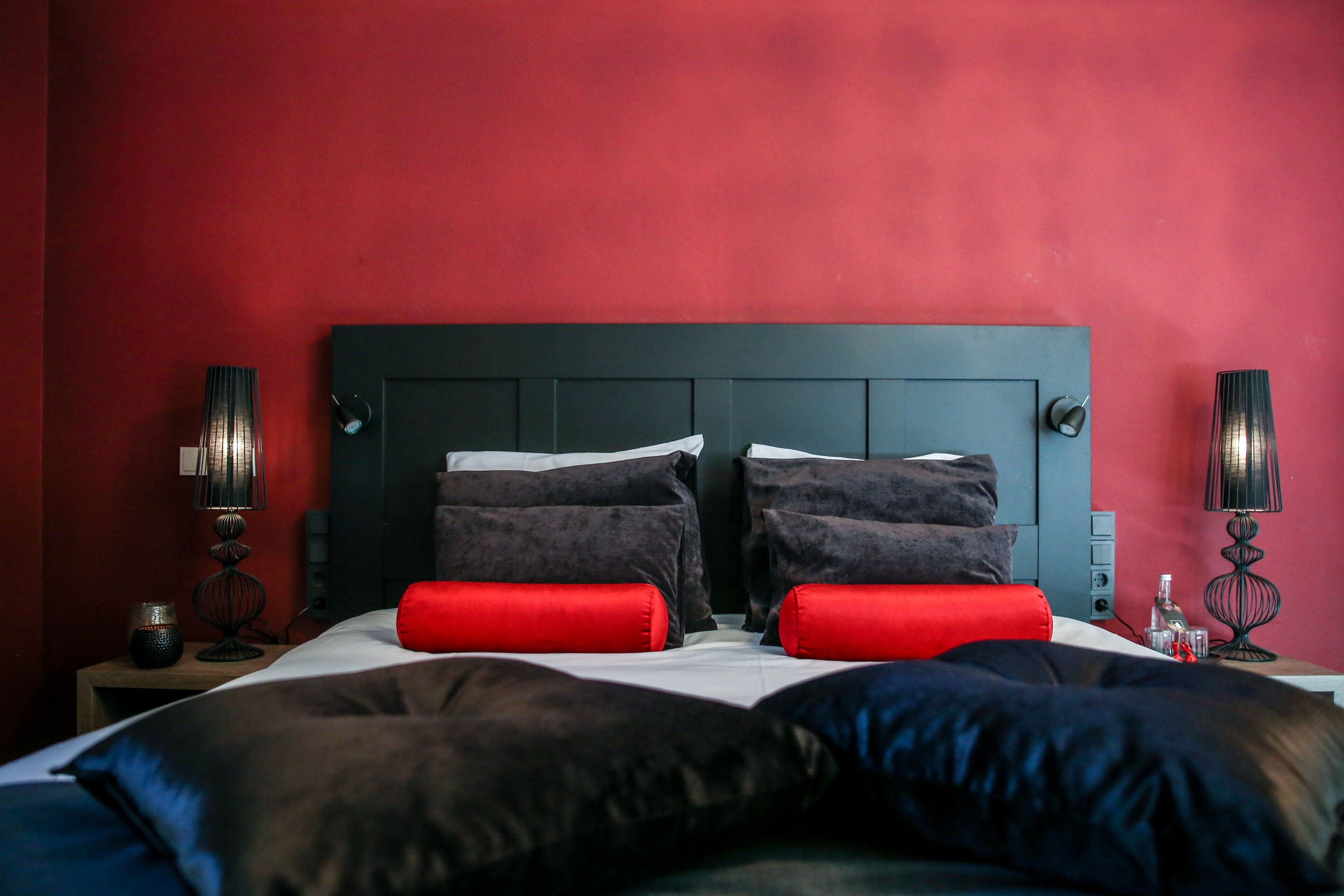 Ein Hotelzimmer mit dunkelbrauner Kopfteil, roten Wänden und zwei Nachttischen mit Lampen.