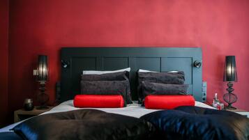 A hotel room with a dark headboard, red walls, and two bedside tables with lamps.