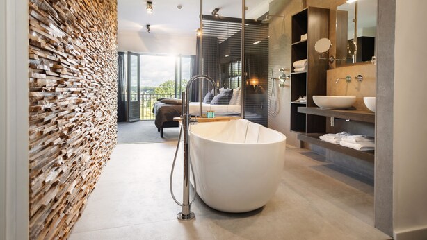 Een moderne badkamer met een groot bad, een houten wand en uitzicht op de omgeving.