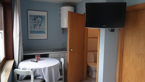Une pièce comprenant une table blanche, une chaise, un téléviseur, un lavabo et des toilettes.