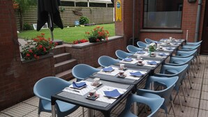 Un patio al aire libre con una larga mesa dispuesta para comer, rodeada de sillas azules.