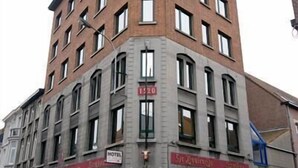 Un edificio en esquina con varios pisos, una entrada visible y un letrero que indica un hotel.