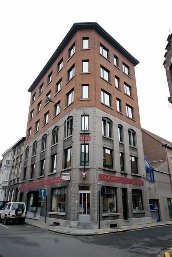 Un immeuble d’angle à plusieurs étages, doté d’une entrée bien visible et d’une enseigne indiquant qu’il s’agit d’un hôtel.