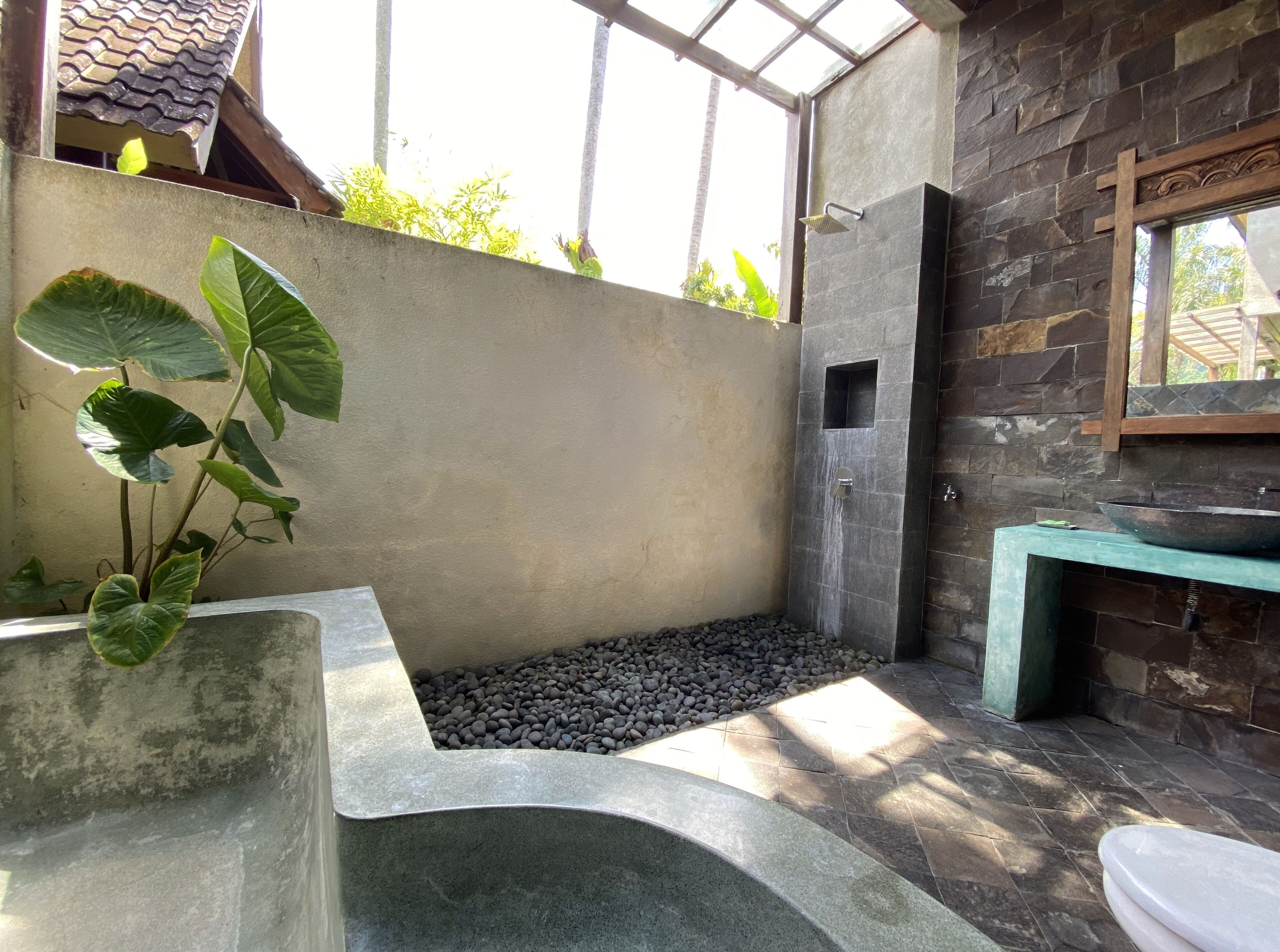 Un baño con pared de piedra, una ventana pequeña y una planta.