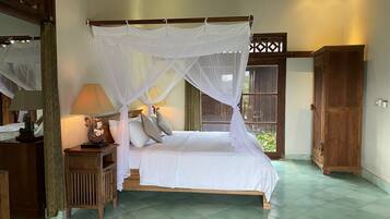A bedroom with a four-poster bed, a nightstand, a lamp, and a wooden wardrobe.