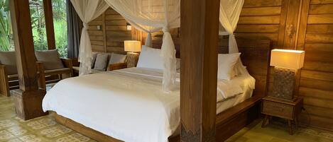 A wooden four-poster bed with a canopy, two bedside lamps, and a patterned floor.