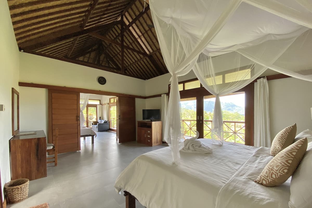 Un dormitorio con una cama grande, televisión y balcón con vistas.