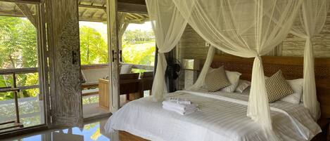 Un dormitorio amplio con una cama grande, ropa de cama blanca y un dosel.