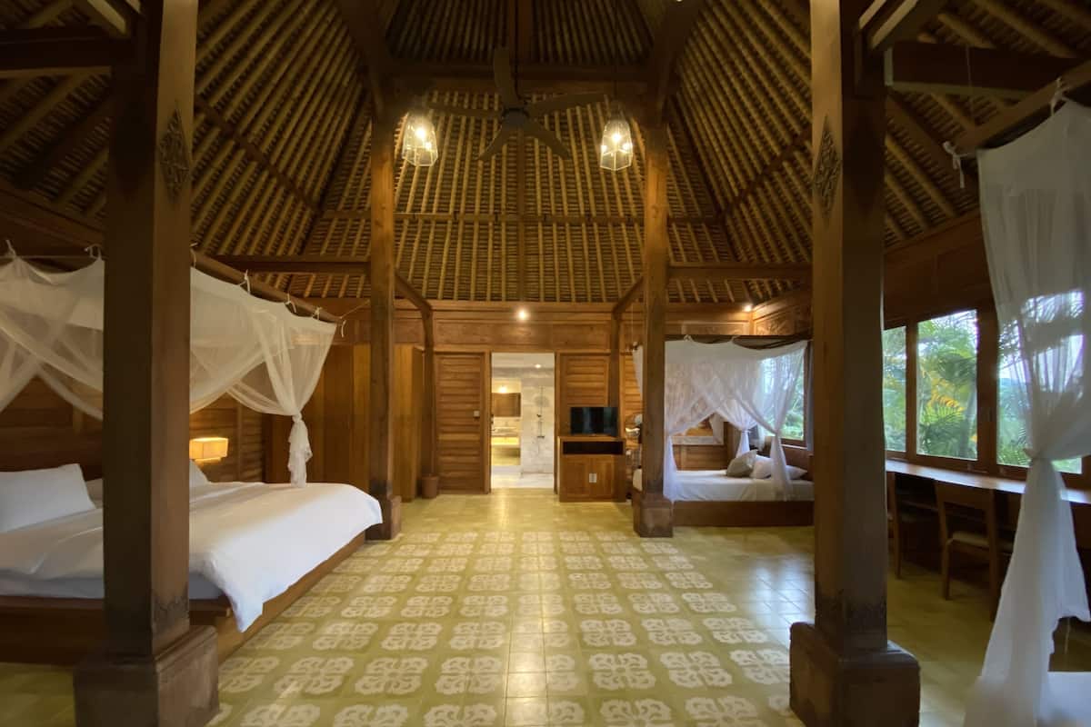 Una habitación con dos camas, cada una con dosel, techo de madera y suelo estampado.