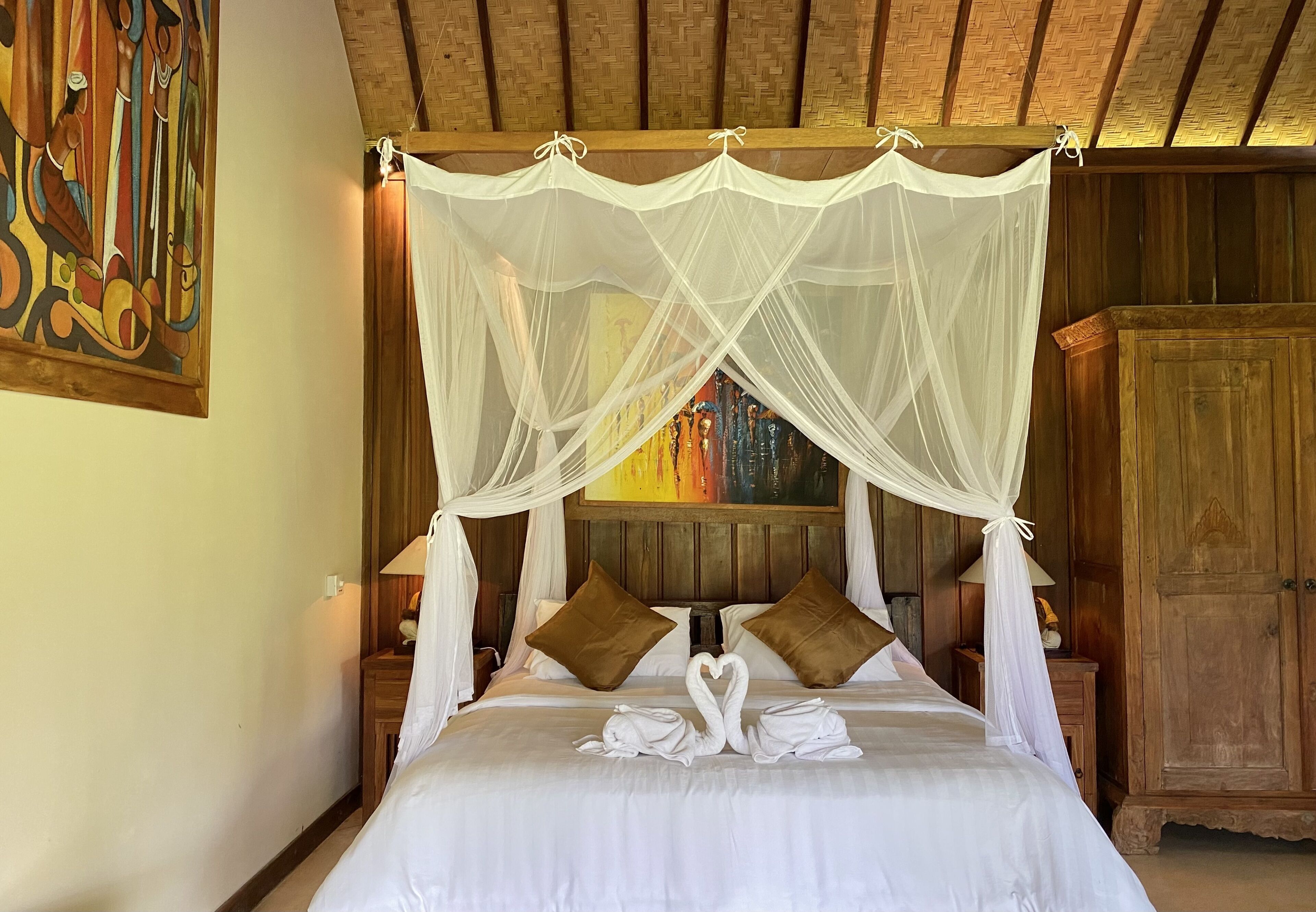 A bed with white linens, a canopy, and two brown pillows.