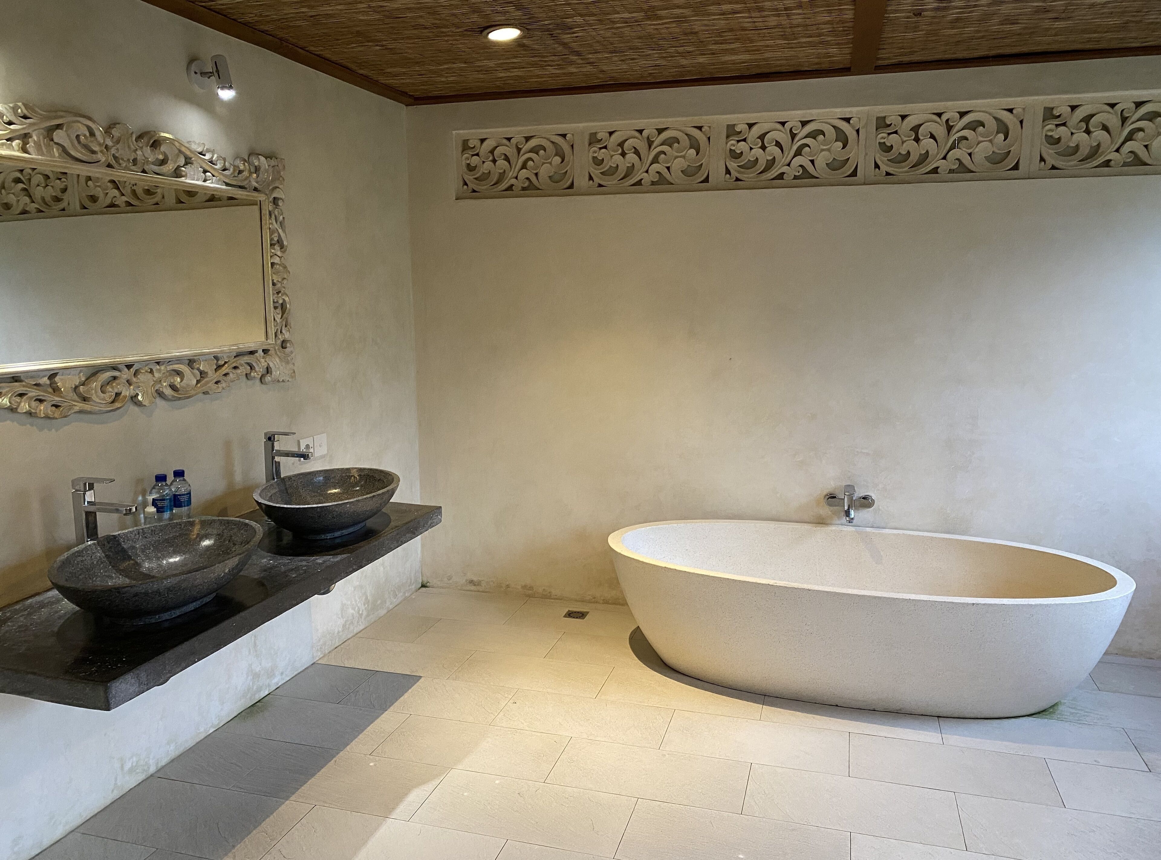 Ein modernes Badezimmer mit einer freistehenden Badewanne, zwei Marmorwaschbecken und einem großen Spiegel.
