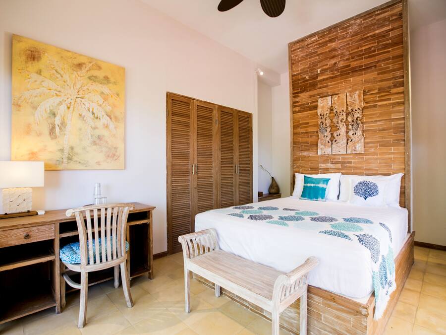 Un dormitorio con una cama, un escritorio de madera, sillas y un cuadro grande en la pared.