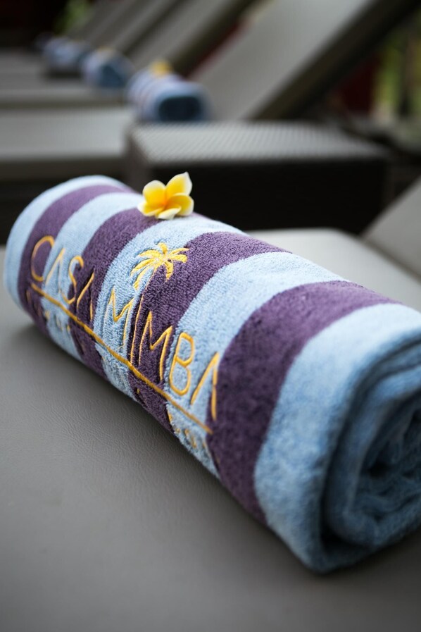 A rolled towel with embroidered text and a flower, placed on a surface.