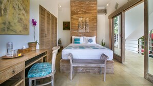 Ein Schlafzimmer mit einem großen Bett, Holzmöbeln, einem Deckenventilator und Blick ins Freie.