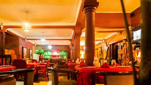 A restaurant interior with multiple tables and chairs, a bar area, and a ceiling fan. - Cari Hotel (Kigali)