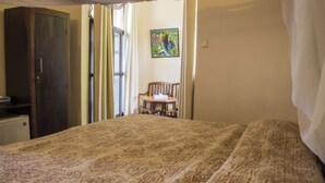 Une pièce comprenant un lit, une chaise, un bureau et une armoire.