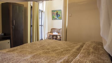 Una habitación con cama, una silla, un escritorio y un armario.