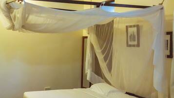A room with a bed under a canopy, a wooden ceiling, and a wall-mounted picture.