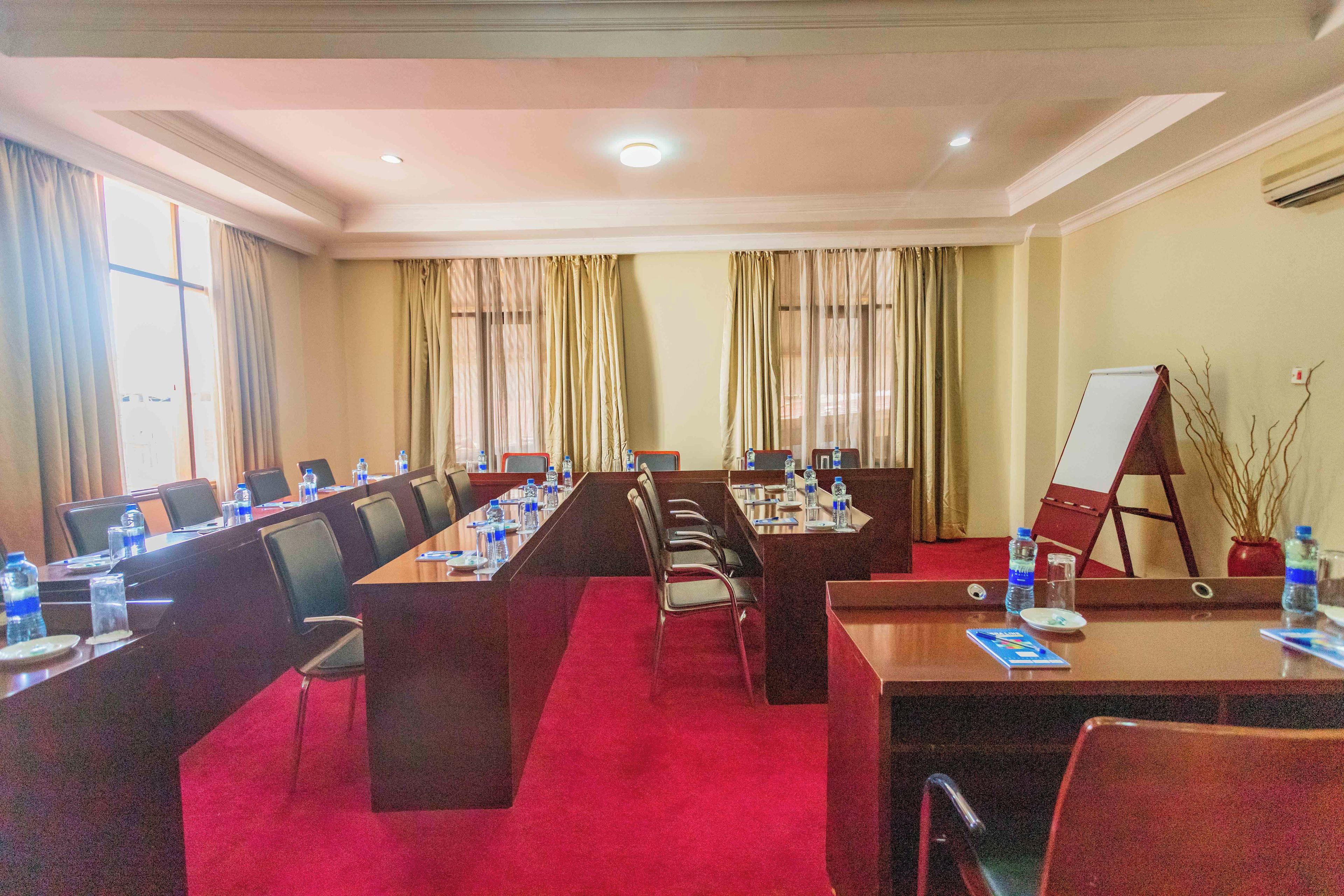 Une salle de conférence avec une longue table, des chaises et un tableau blanc.