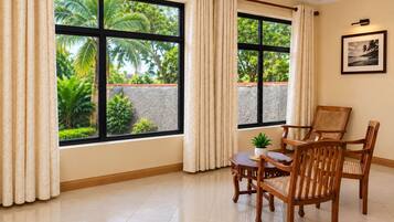 Una habitación con ventanas amplias, una mesa de comedor con sillas, una planta en maceta y un cuadro en la pared.