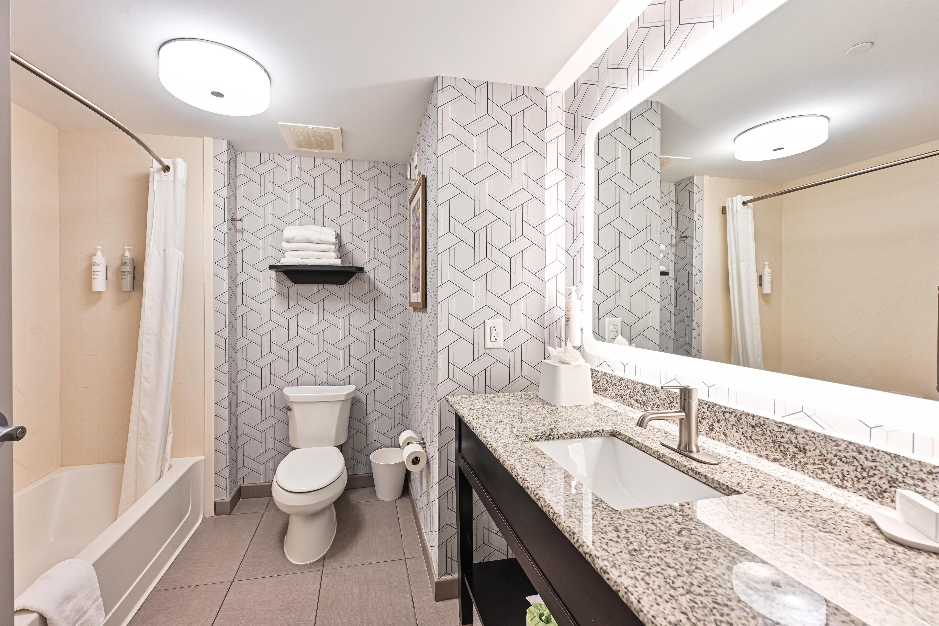 A modern bathroom with a shower, toilet, and sink.